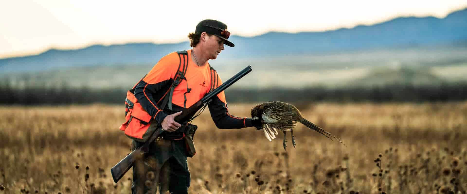 hunter-in-orange-holding-fierce-alpha-shotgun-with-mountain-backdrop-at-mogle-ranch